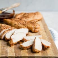 Smoked chicken breast on a wooden cutting board.