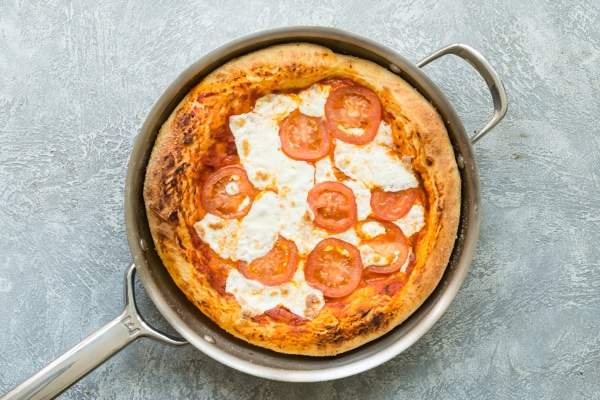 Overhead picture of a margherita pizza in a skillet after being baked.