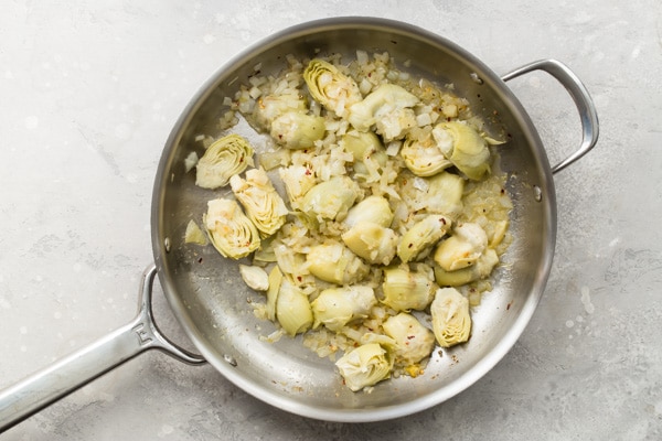 An overhead shot of artichoke pasta being cooked in a skillet.