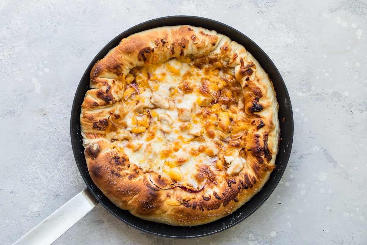 An overhead shot of a baked BBQ chicken skillet pizza in a cast iron skillet.