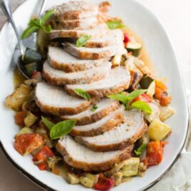 Pork loin with ratatouille on a white platter.