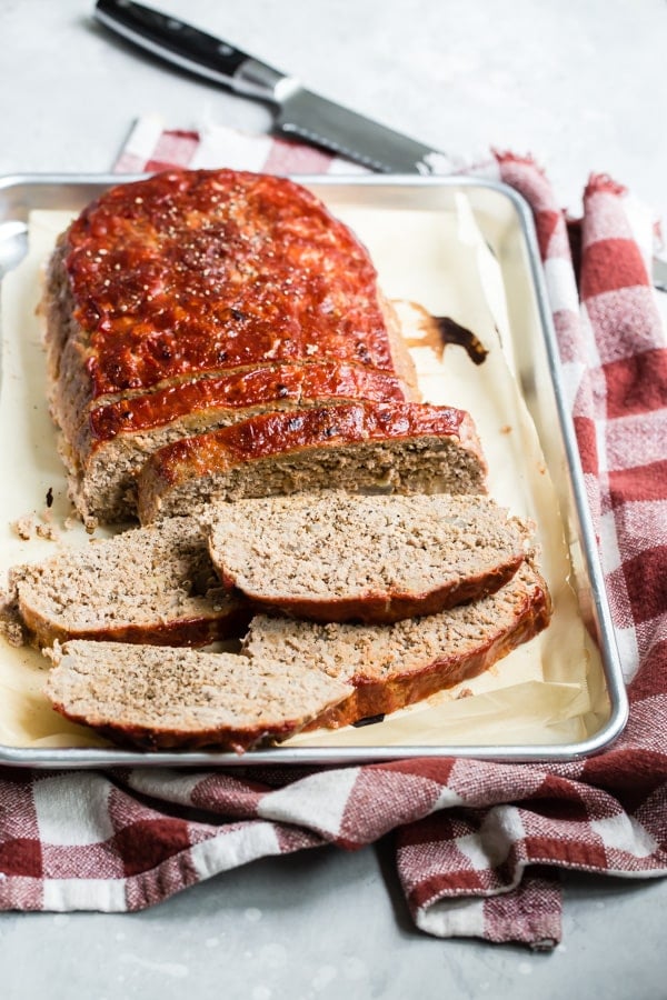 An angled shot of sliced turkey meatloaf on a baking pan.