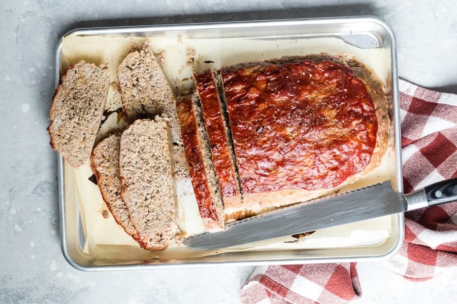 An overhead shot of sliced turkey meatloaf on a baker's sheet.