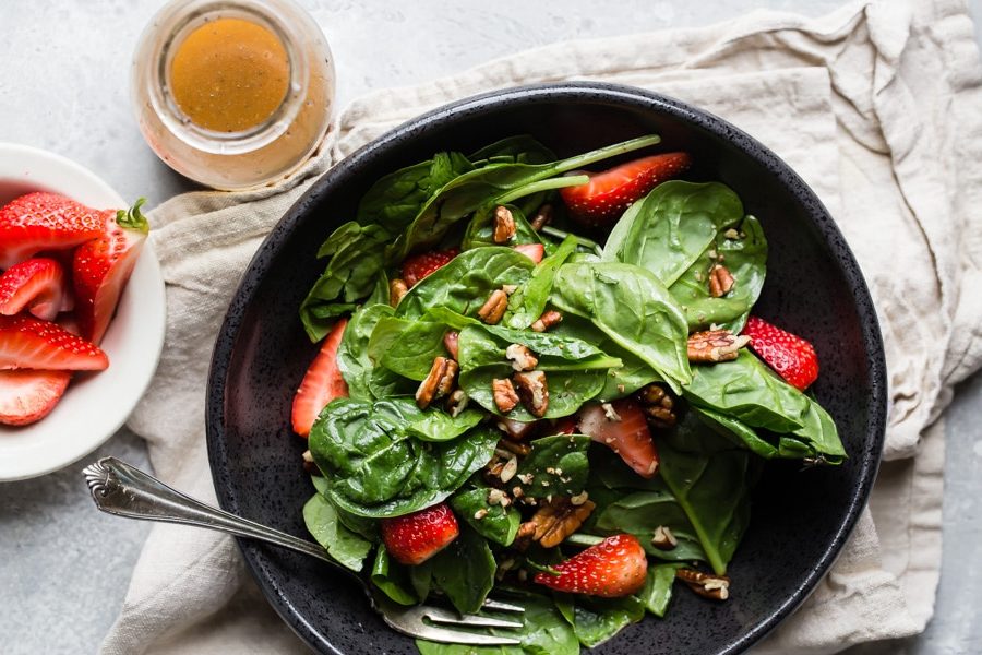 Strawberry spinach salad in a black bowl.