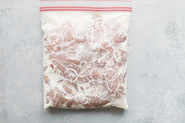 Chicken marinating in a plastic bag.
