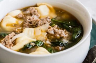Sausage tortellini soup in a white bowl.