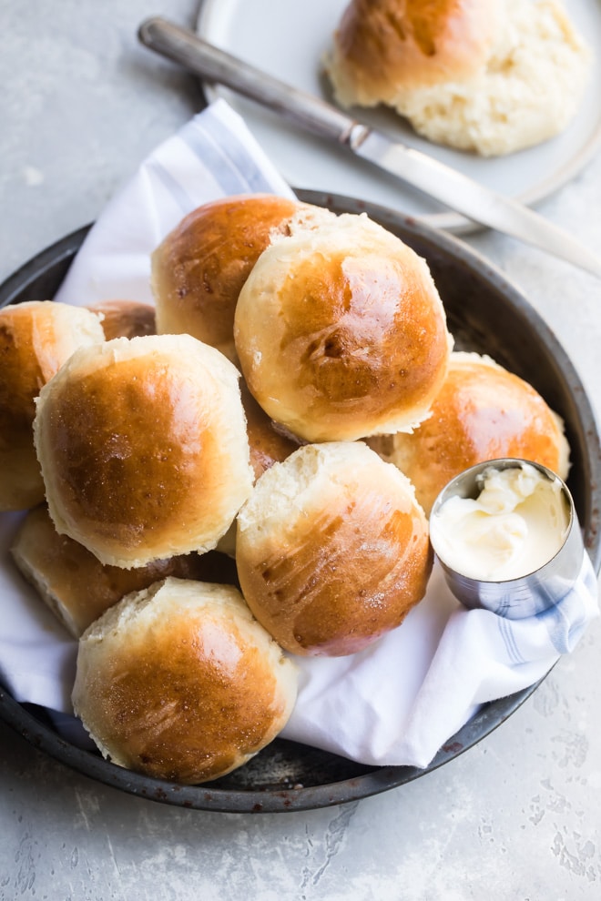 A pan of soft yeast dinner rolls with a side of butter.