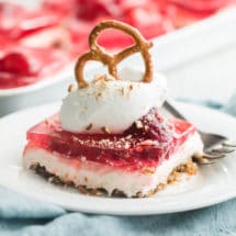 A serving of strawberry pretzel salad on a white plate with a fork.
