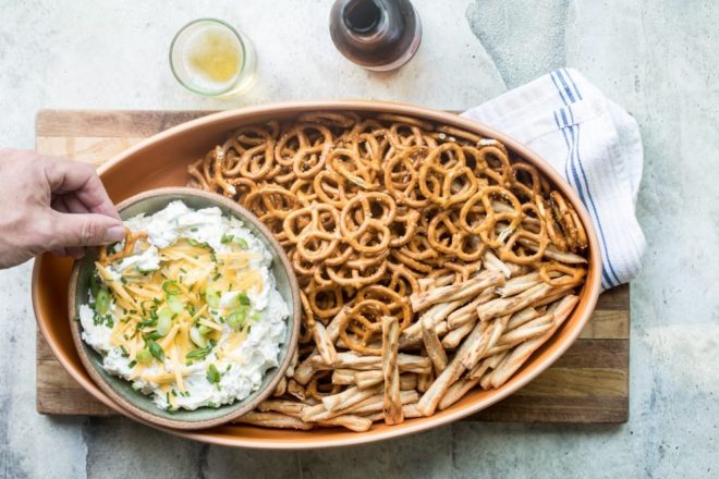 Beer cheese dip in a brown bowl with pretzels.