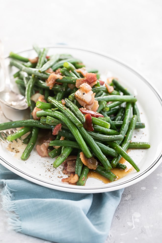 Green beans with bacon on a white platter.