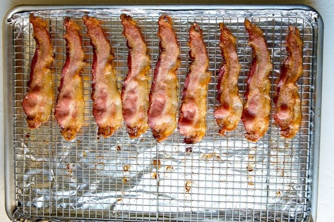 Cooked bacon strips on a baking sheet.