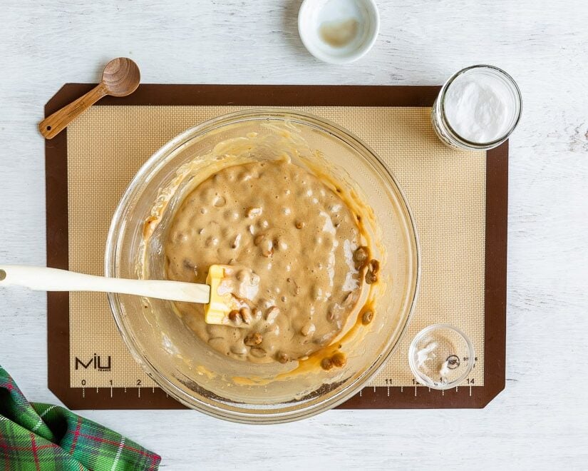 Microwave peanut brittle in a clear glass bowl with a rubber spatula.