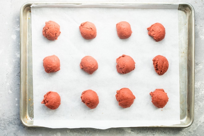 Peppermint cookie dough balls raw on a baking sheet.