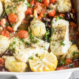 Baked cod in a white baking dish.