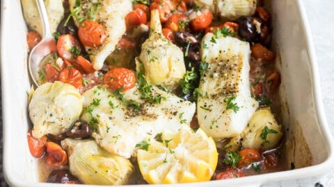Baked cod in a white baking dish.