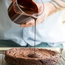 Chocolate glaze being poured onto a flourless chocolate cake.
