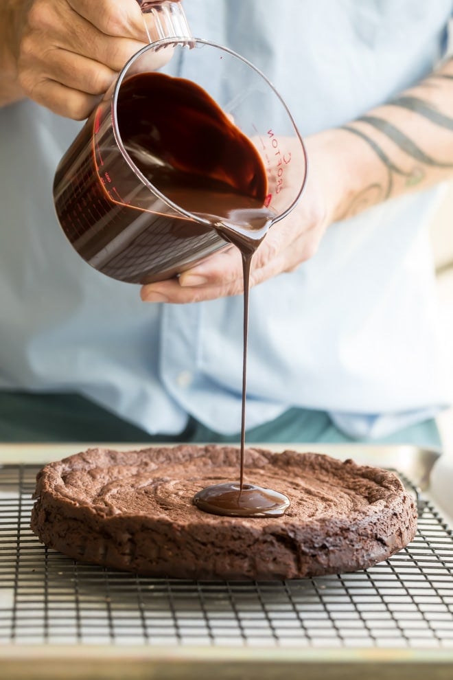 Chocolate glaze being poured onto a flourless chocolate cake.
