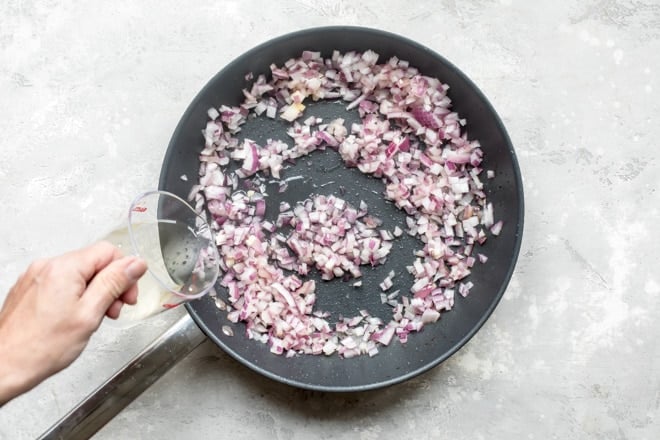 Red onion cooking in a black skillet.