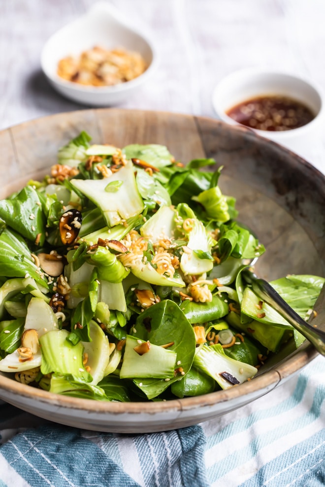 Baby bok choy salad with sesame dressing in a wooden bowl.