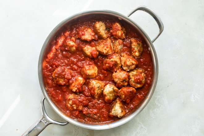 Meatballs and pasta sauce in a silver skillet.