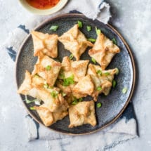 Cream cheese wontons on a black plate.