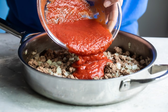 The best sloppy joe sauce being added to cooked ground beef and onion mixture.