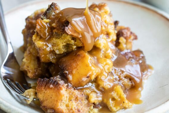 Bread pudding with caramel sauce on a white plate.
