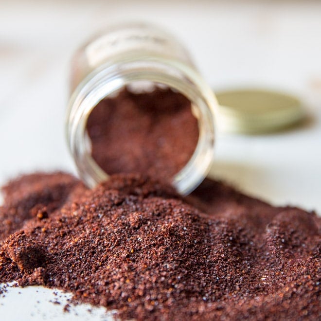 Ancho chile powder dumped out of a glass jar onto a counter.