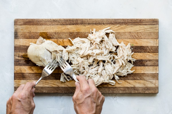 Shredded white turkey on a wooden cutting board.