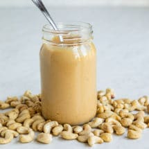 Cashew Butter in a mason jar with a spoon resting in it.