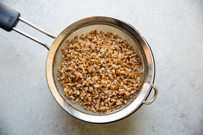 Farro being drained in a colander.