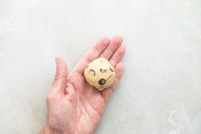 Someone holding a ball of cookie dough in their palm.