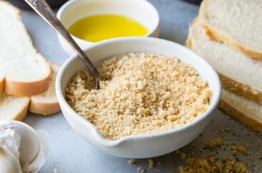 Homemade breadcrumbs in a white bowl with a spoon.