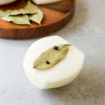 Half of an onion with a bay leaf attached to it with whole cloves.