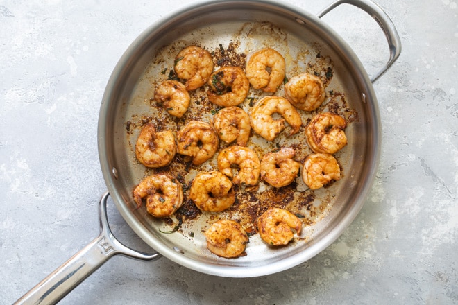 Shrimp being cooked on a silver pan.