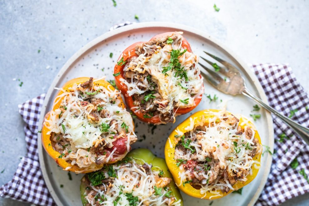 Four stuffed peppers on a white plate with a fork.