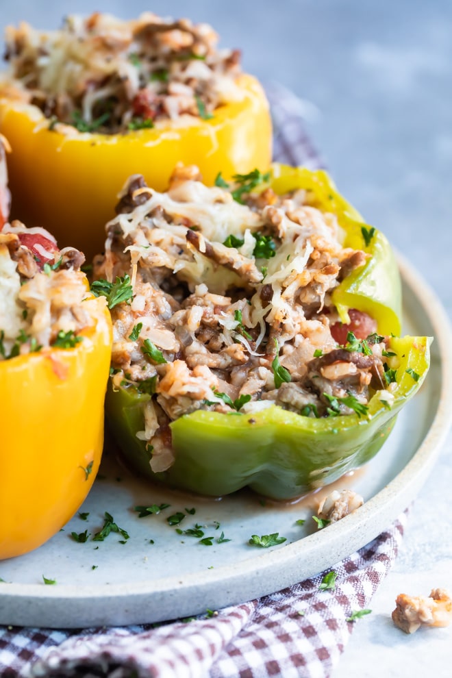 Four stuffed peppers on a white plate.