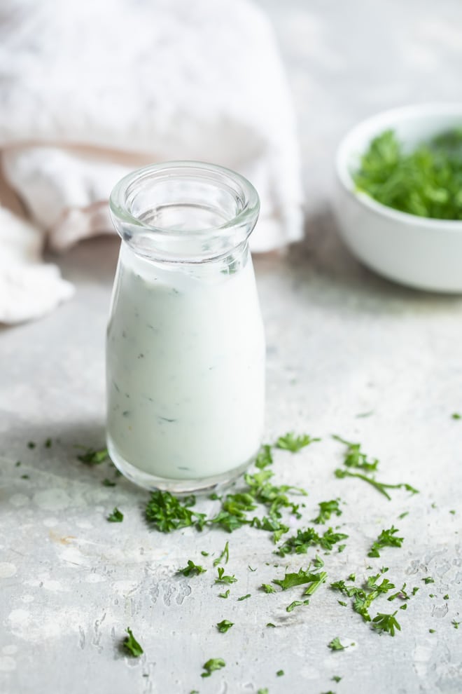 Homemade Ranch dressing in a clear glass bottle.