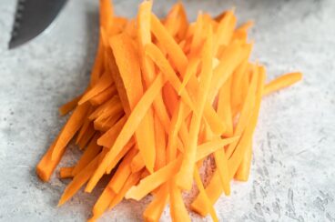 A stack of julienne carrots on a marble countertop.