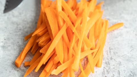 A stack of julienne carrots on a marble countertop.