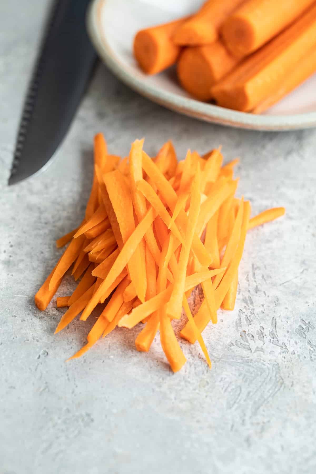 A pile of Julienned carrots on a countertop.