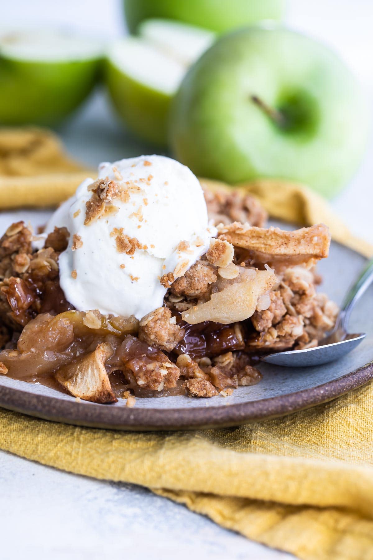 Apple crisp on a plate with a scoop of ice cream on top.