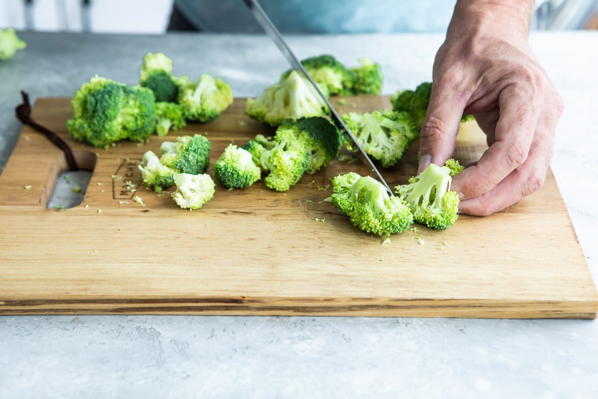 Cut up broccoli on a cutting board.