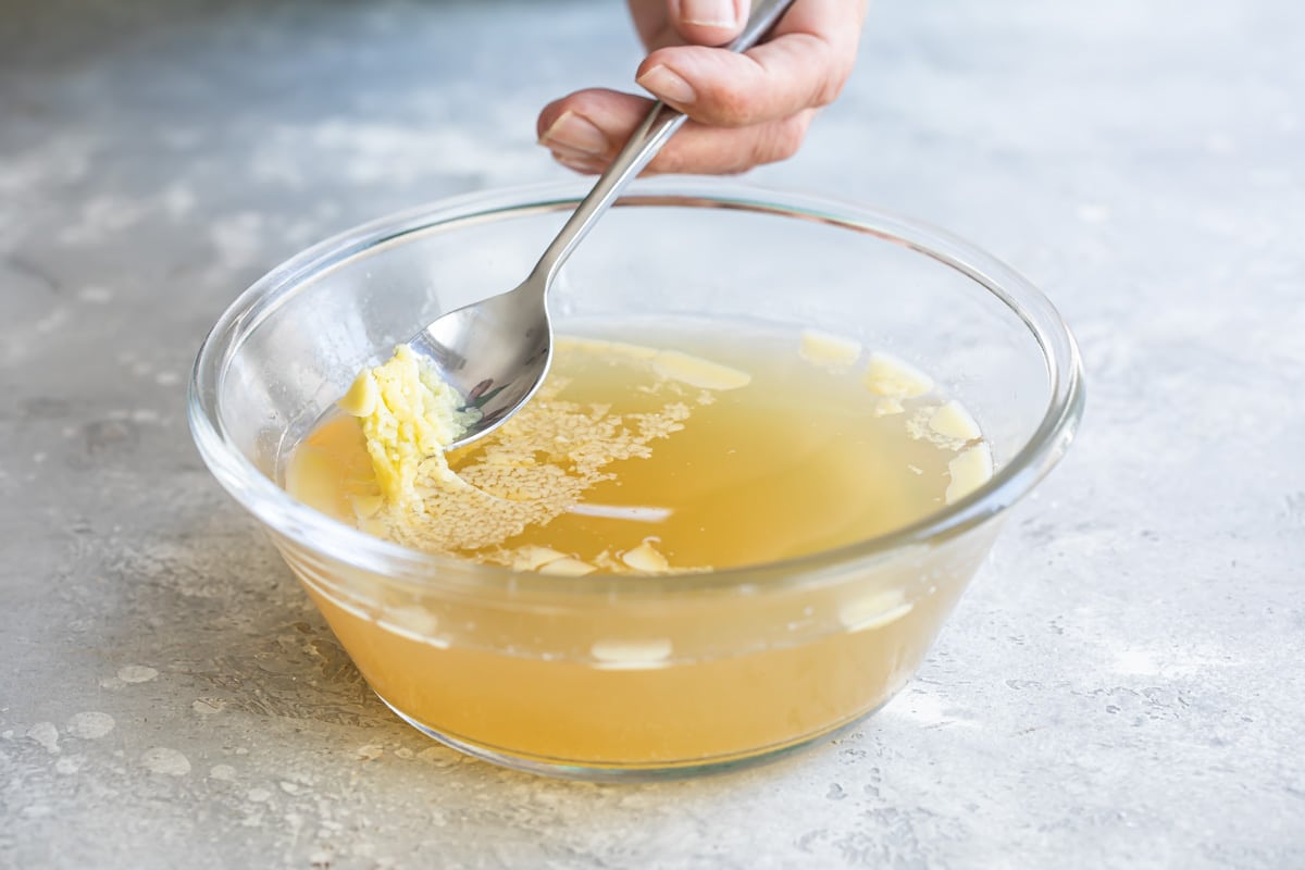 Chicken fat being scooped off of the top of chicken broth.