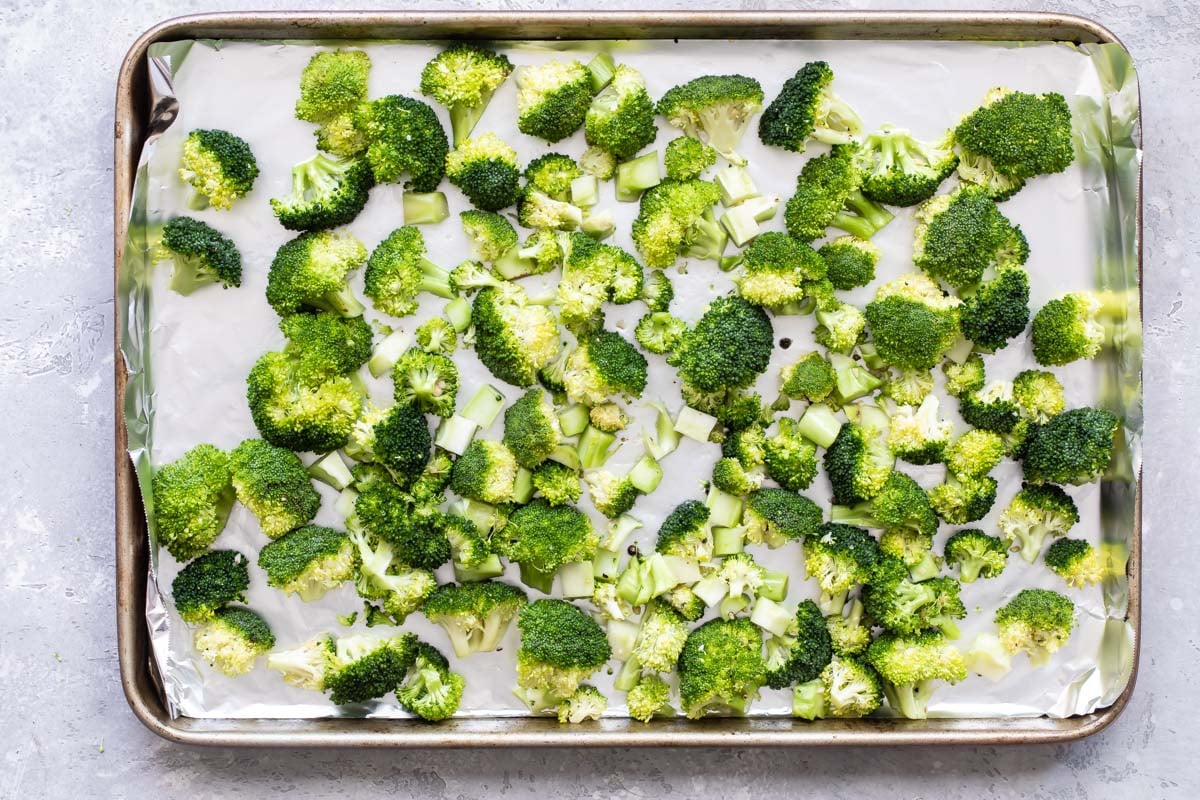 Raw Broccoli and lemon on a baking sheet.