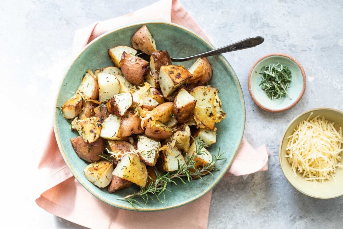 Roasted rosemary potatoes in a teal bowl.