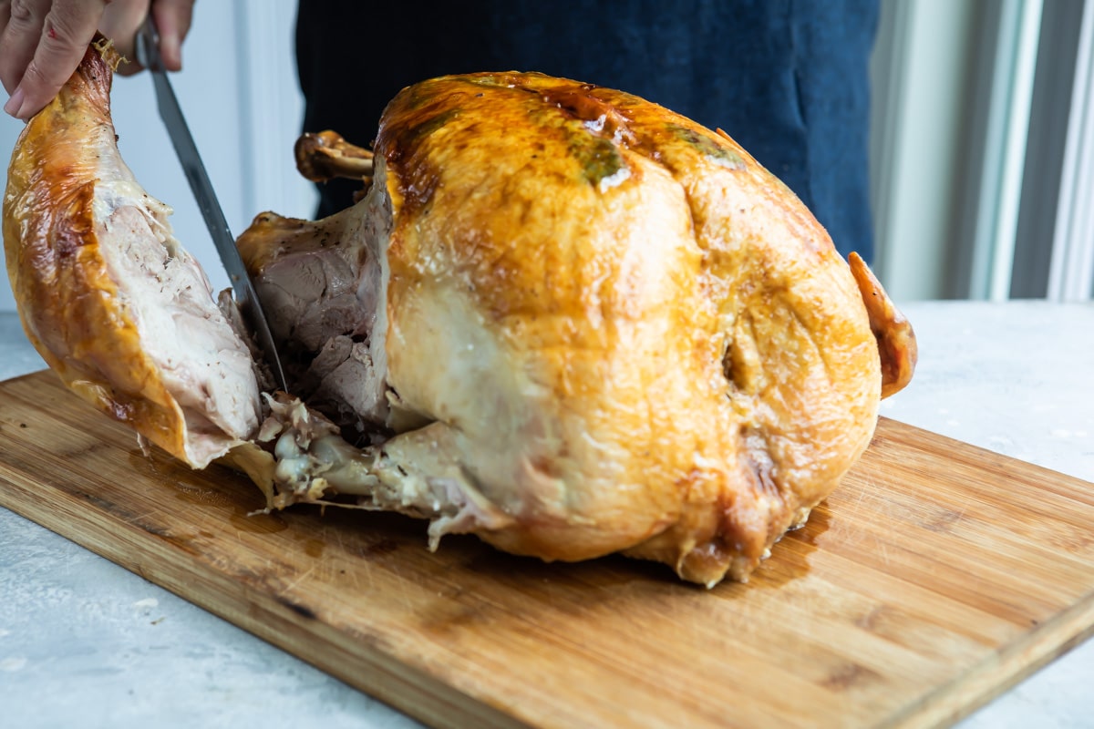 Carving a roasted turkey leg off a full turkey.
