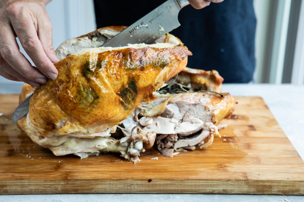 Carving roasted turkey breast off a whole turkey.