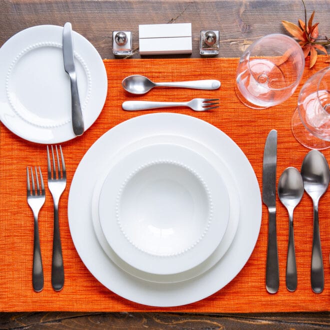 A place setting on an orange placemat.