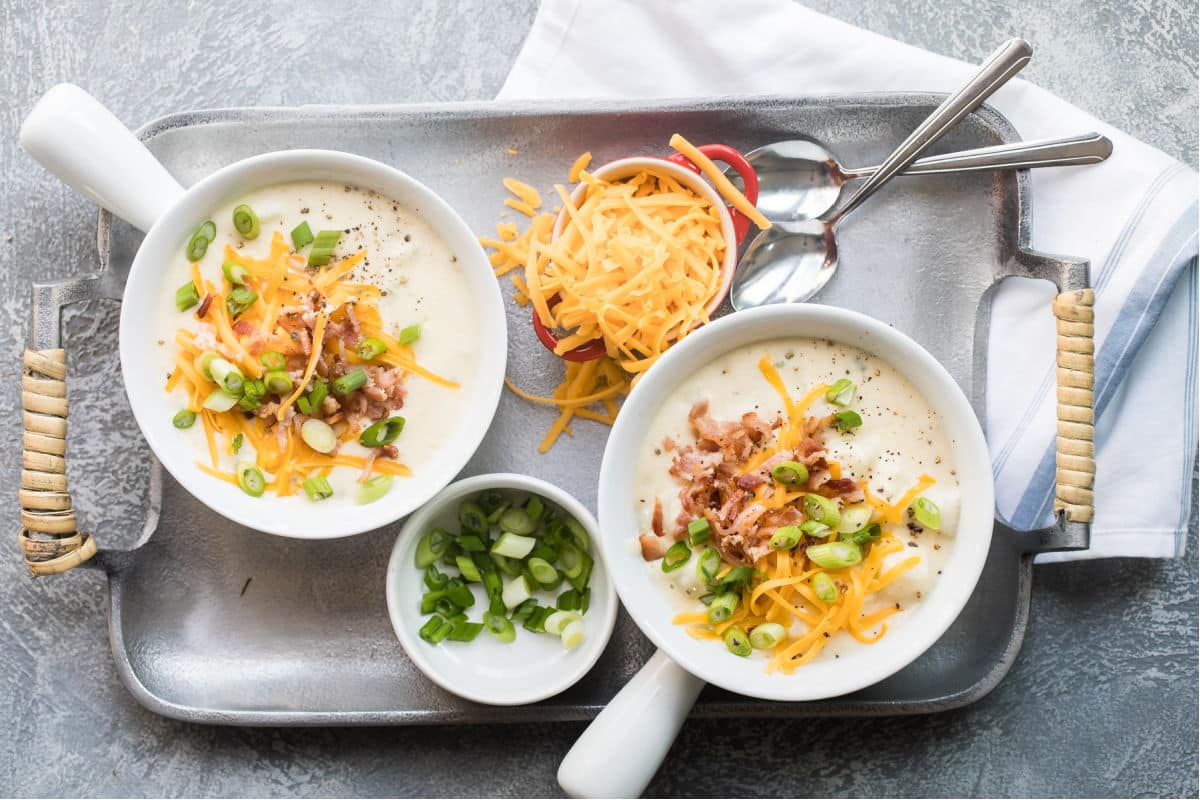 Loaded baked potato soup in two white bowls.